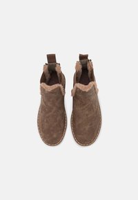 Bruna ankelstövlar i strukturerat mocka med fuskpälskant, elastiska sidor och dekorativ söm längs sulan.