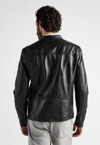 Schwarze Lederjacke mit glatter Textur, klassischem Kragen, Reißverschlussmanschetten und genähten Paneldetails auf dem Rücken.