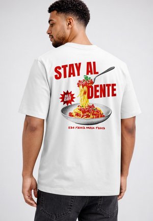 Mann trägt ein weißes T-Shirt mit rotem Text "Stay Al Dente" und einer Illustration von Spaghetti auf einer Gabel über einem Teller Pasta.