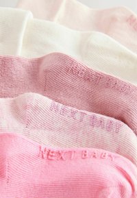 Pięć par skarpetek dla niemowląt w różnych odcieniach: białym, jasnoróżowym i ciemnoróżowym. Tkanina o teksturowanym splocie z napisem „NEXT BABY” utkanym.