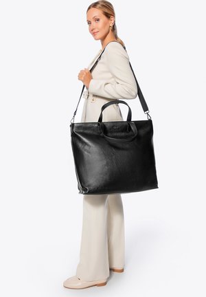 Bolso tote de cuero negro con asas dobles y correa de hombro ajustable. Textura suave, cuerpo espacioso y marca sutil en la parte frontal.