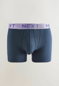 Temno modri bokserji z mehko tkanino, ki imajo svetlo vijolični pas z oznako "NEXT" v krepkih črkah. Vključujejo sprednje odpiranje.
