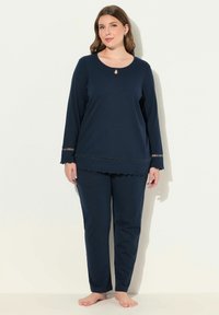 Marineblaues Pyjama-Set aus weicher Baumwolle, bestehend aus einem Langarm-Oberteil mit einem Schlüssel-ausschnitt und gewelltem Saum, kombiniert mit passenden Hosen.