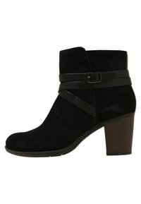 Musta mokkanahkainen nilkkuri pyöreällä kärjellä, kahdella mustalla nahkahihnalla ja paksulla korolla. Ominaisuuksiin kuuluu sileä pinta ja minimalistinen muotoilu.