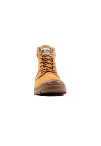 Bottine de cheville imperméable beige avec semelle en caoutchouc marron, bout rond, œillets en métal et lacets. Comprend une étiquette de marque sur la languette.
