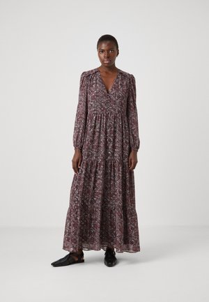 Maxi jurk in donkerrood met bloemendruk. Lange poffende mouwen, V-hals en gelaagd ontwerp. Gecombineerd met zwarte platte sandalen.