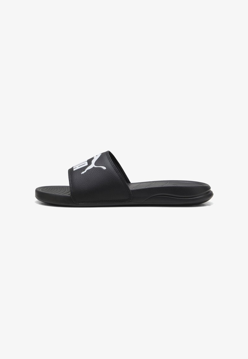 Sandale noire style slide avec semelle rembourrée et large bride présentant le logo blanc Puma sur le dessus, vue de profil.