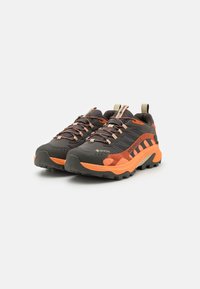 Buty trekkingowe Merrell w ciemnoszarym kolorze z pomarańczowymi akcentami, teksturowaną gumową podeszwą i wzmocnionym piętem. Posiadają wzorzyste sznurówki i logo.