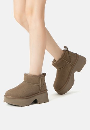 Brown suede ankle boots with a chunky rubber sole and textured accents. Soft interior lining with a pull tab at the back for easy wearing.