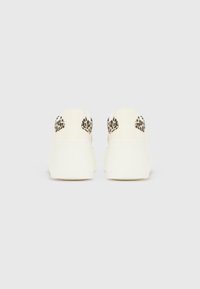 Baltas sporta kurpes ar leoparda raksta akcentiem papēdī, ar gludu materiālu un zemu siluetu.