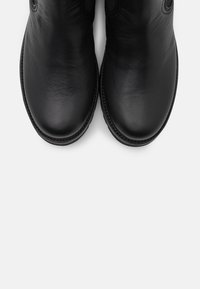 Svarta läderankelstövlar med rundade tår, slät yta och sydda detaljer längs kanterna. Har elastiska sidopaneler för en bra passform.