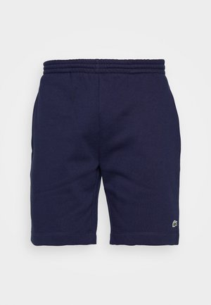 Shorts en coton bleu marine avec une taille élastique, arborant un petit logo vert sur le bas de la jambe gauche et une texture lisse.