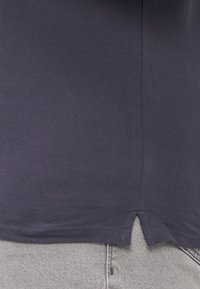 Marineblå skjorte med en teksturert finish, med splittet nederkant og stykke accenter. Kombinert med lysegrå jeans.