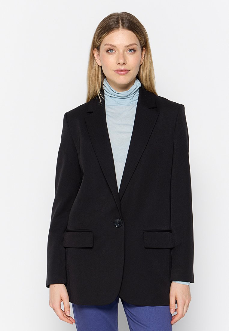 Schwarze Blazer mit geknöpften Revers, Ein-Knopf-Verschluss, zwei vorderen Taschen und glatter Stoffoberfläche, getragen über einem hellblauen Rollkragenpullover.