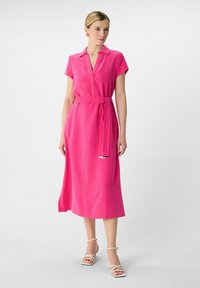 Rosas, kurzärmliges Kleid mit einem V-Ausschnitt und einem gebundenen Taillengürtel. Glatte Textur, knöchellang und aus leichtem Stoff. Minimalistisches Design.