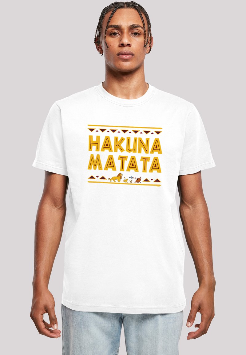 Hvit bomulls-kjorte med teksten "HAKUNA MATATA" i gul skrift, akkompagnert av tribal mønstre og dyregrafikk nederst.