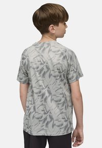 Pilkos spalvos trumpomis rankovėmis marškinėliai su abstrakčiu juodu lapų raštu, pagaminti iš lengvos, kvėpuojančios medžiagos, turintys laisvą siluetą.