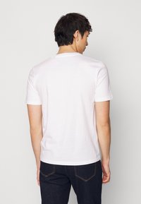 Camiseta blanca de manga corta hecha de suave algodón, con un cuello redondo y un diseño simple sin gráficos ni patrones.