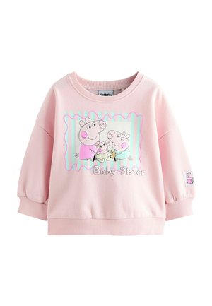 Vaaleanpunainen collegepaita pyöreällä kaula-aukolla ja puffihihnoilla, jossa on sarjakuvaprintti sioista ja teksti "Baby Sister" raidallista taustaa vasten.