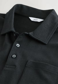 Sort polo-shirt med en klassisk krave, tre knapper og en brystlomme. Fremstillet af tekstureret stof med en afslappet pasform.