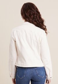 Witte denim jacket met ingewikkelde borduurpatronen, kraag en knoopaccenten. Verkorte pasvorm, aansluitende mouwen en stikseldetails.