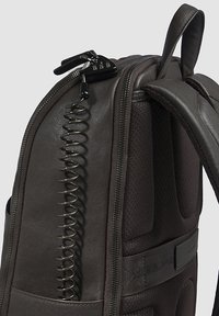 Donkere grijze leren rugzak met een gestructureerd oppervlak, een gedraaide ritsdetail, een gevoerde achterkant en een verstelbare band.