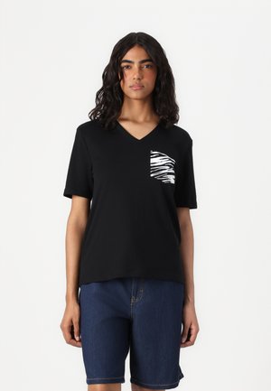 T-shirt noir à col en V en tissu doux avec des manches courtes, présentant une poche décorée d'un motif zèbre sur le côté gauche. Associé à un short en denim.