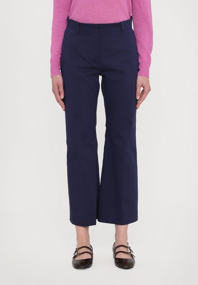 Navy cropped trousers with a tailored fit, featuring a flat front, belt loops, and side pockets, paired with black strapped shoes.