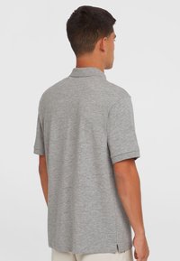 Polo shirt gris à manches courtes, fabriqué en tissu mélangé, avec un col classique et des fentes sur les côtés au niveau de l'ourlet pour plus de confort.