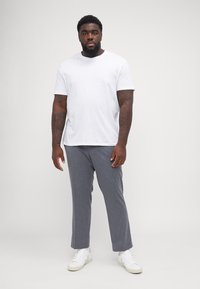 Hvit bomull T-skjorte paret med grå teksturerte bukser og hvite sneakers, med avslappet passform og straight leg design.