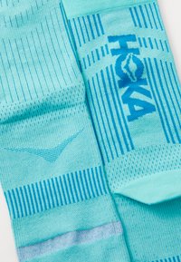 Pair of light blue athletic socks with dark blue vertical stripes and "TOXA" text woven on one sock.