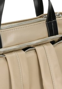 Beige stoffen tas met zwarte leren accenten, voorzien van meerdere met rits afgesloten compartimenten en een zachte geplooide textuur aan de voorkant. Zilveren hardware duidelijk zichtbaar.