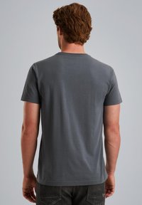 Camiseta de algodón gris con cuello redondo y mangas cortas, textura suave, diseño básico y sin patrones o acentos visibles en la parte posterior.