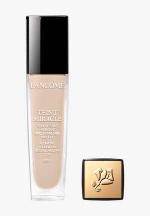 Fond de teint Lancôme Teint Miracle dans un flacon rectangulaire transparent avec un couvercle noir. Comprend un compact avec un couvercle doré arborant un design floral.