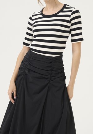Zwart-wit gestreept geribd topje met korte mouwen, gecombineerd met een hooggetailleerde zwarte rok met geplooide details en een gladde textuur.