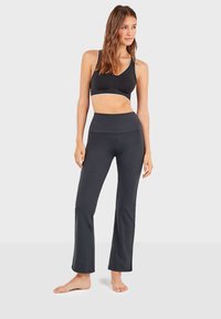 Ensemble de sport noir comprenant un haut court avec une finition blanche et un legging évasé taille haute. Tissu doux avec une texture lisse.