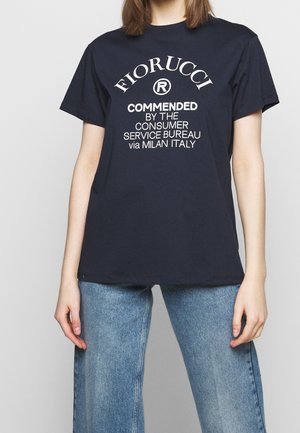 T-shirt en coton bleu marine avec texte blanc : « FIORUCCI RECOMMANDÉ PAR LE BUREAU DU SERVICE CONSOMMATEUR via MILAN ITALIE », avec un col rond classique.