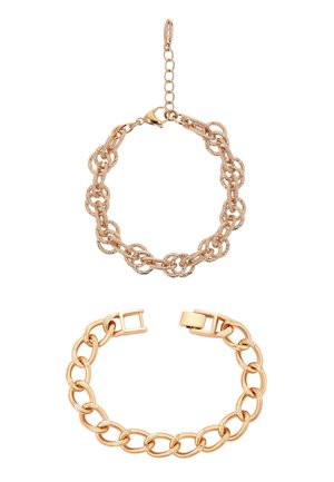 Dwie złote bransoletki łańcuchowe o różnych stylach ogniw, jedna z teksturowanymi masywnymi ogniwami i małym łańcuszkiem przedłużającym, druga ze gładkimi owalnymi ogniwami i zapięciem.