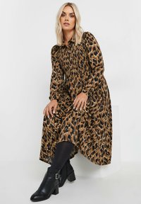 Sukienka w panterkę wykonana z lekkiej tkaniny, z długimi rękawami, marszczonym topem i warstwową, podszewkową spódnicą. Noszona z czarnymi botkami za kostkę.