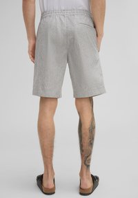 Gestreifte Shorts in Grau und Weiß, mit einem elastischen Bund, Seitentasche und gesäumten Beinen, aus leichtem Stoff gefertigt.