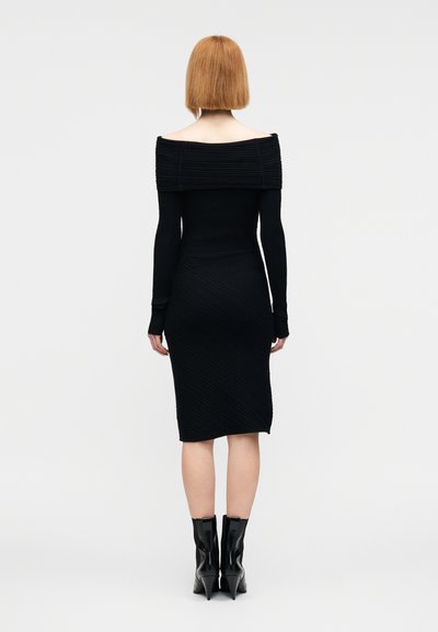 Μαύρο ριμπ μίντι φόρεμα με ντεκολτέ έξω από τους ώμους και μακριά μανίκια. Διαθέτει υφασμένο μοτίβο και εφαρμοστή σιλουέτα. Φοριέται με μαύρα μποτάκια έως τον αστράγαλο.