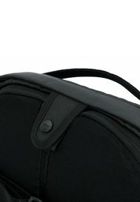 Zaino in tessuto nero con superficie testurizzata, dotato di manico superiore, chiusura con bottone a pressione e materiali a contrasto per una maggiore durata.