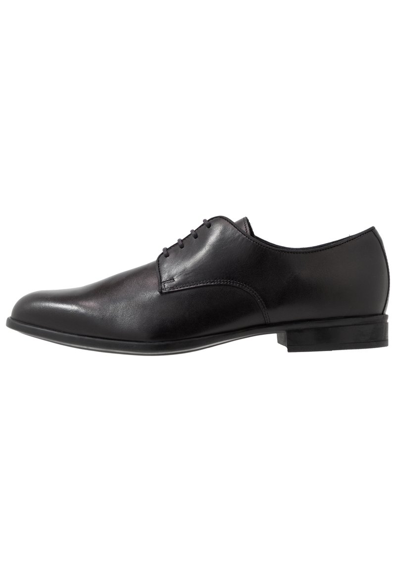 Chaussure habillée en cuir noir à finition lisse, bout arrondi, design à cinq œillets avec lacets, et coutures minimalistes. Talon bas en caoutchouc.