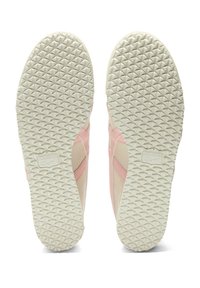 Różowe i kremowe podeszwy sneakerów z teksturowaną białą gumową podeszwą z diamentowym wzorem oraz wytłoczonym logo z boku.