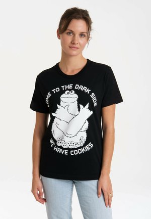Schwarzes Baumwoll-T-Shirt mit einem weißen Grafikbild eines haarigen Charakters mit Keksen, umgeben von dem Text: "Komm auf die dunkle Seite, wir haben Kekse."