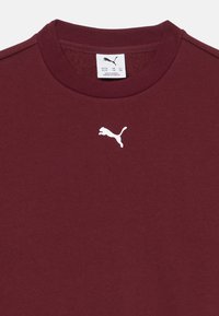 Sweatshirt bordò con scollatura a girocollo e un piccolo logo Puma bianco sul petto. Realizzato in tessuto morbido con una superficie liscia.