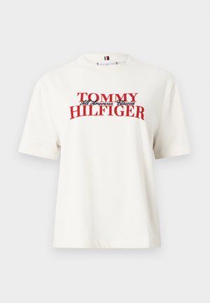 White cotton t-shirt with short sleeves and a crew neck, featuring "TOMMY HILFIGER" in bold red lettering. Notable graphic design.
