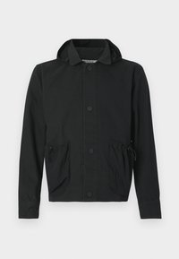 Čierna skrátená bunda z ľahkej tkaniny, s predným zapínaním na gombíky, dvoma vreckami so sťahovacími šnúrkami a kapucňou.