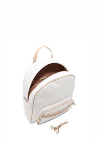 White textured backpack with a rounded shape, beige accents, two zippered compartments, and a decorative charm with clear beads.