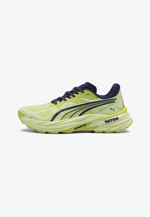 Gele en donkerblauwe Puma hardloopschoen met dikke zool, "NITRO" branding en Puma-logo aan de hielzijde.